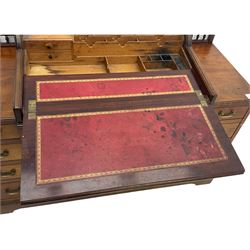 Victorian walnut clerk's desk, raised central section with tambour roll over hinged top, the interior fitted with leather inset writing surfaces, small drawers, document divisions and pen and ink stand, central drawer over double panelled cupboard, flanked by two banks of four graduating drawers, on bracket feet 