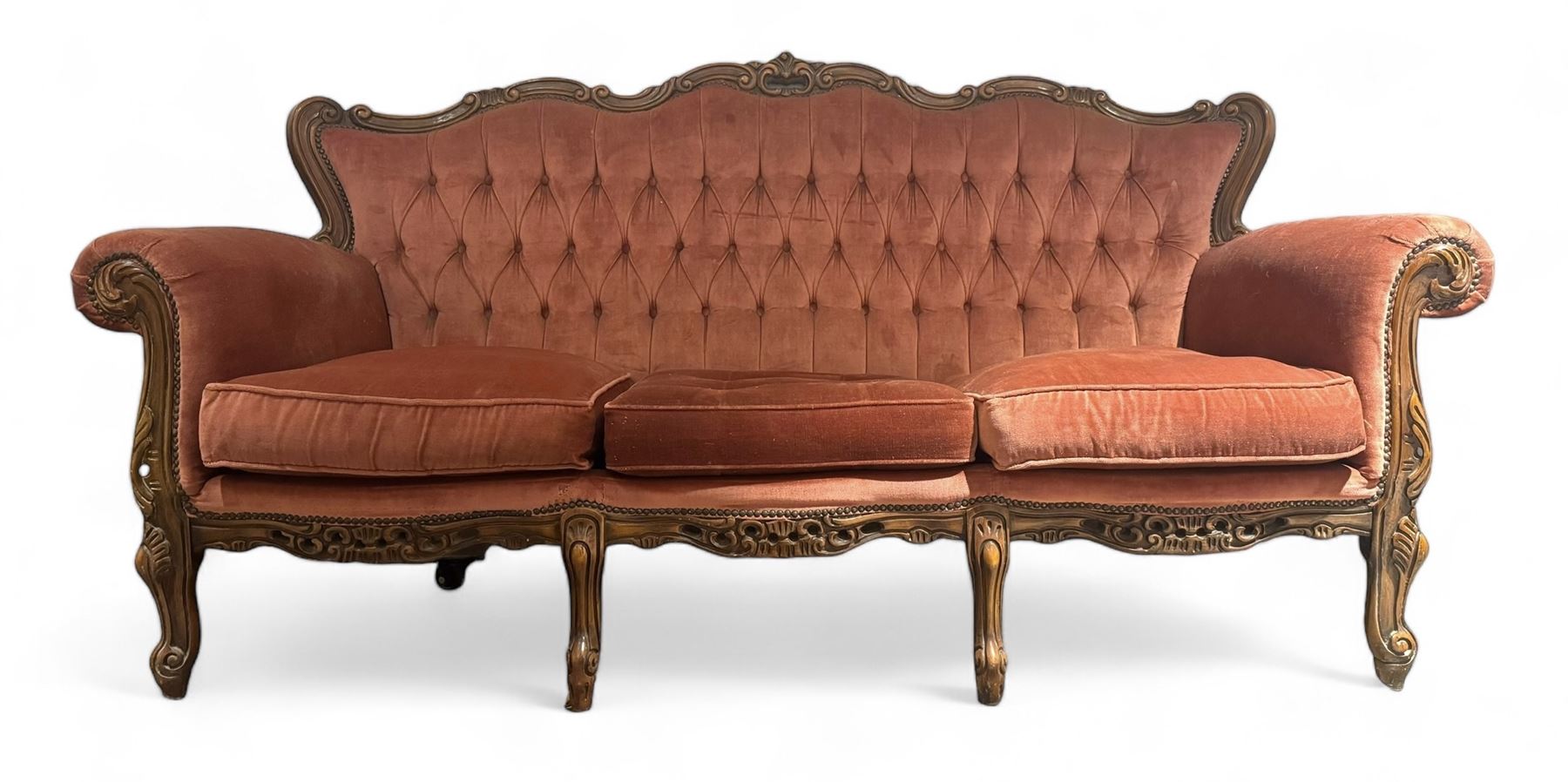 Late 20th century French walnut framed three-seat sofa, high shaped back with floral carved cresting rail, deep-buttoned coral velvet upholstery with loose seat cushions, scrolling arm terminals over moulded walnut frame, raised on cabriole supports