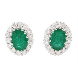 Pair of 18ct white gold oval cut emerald and round brilliant cut diamond stud earrings, st...