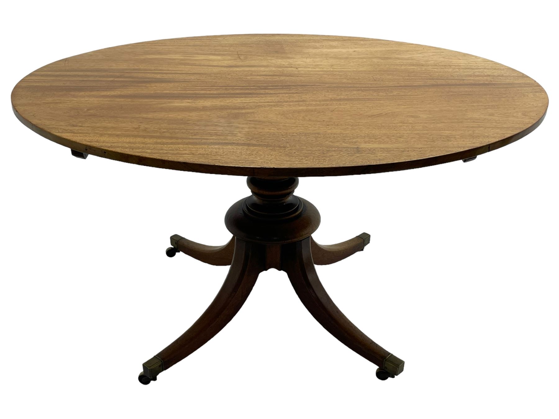 George III mahogany breakfast table, oval tilt-top on turned column with four splayed supports, fitted with brass cups and castors 