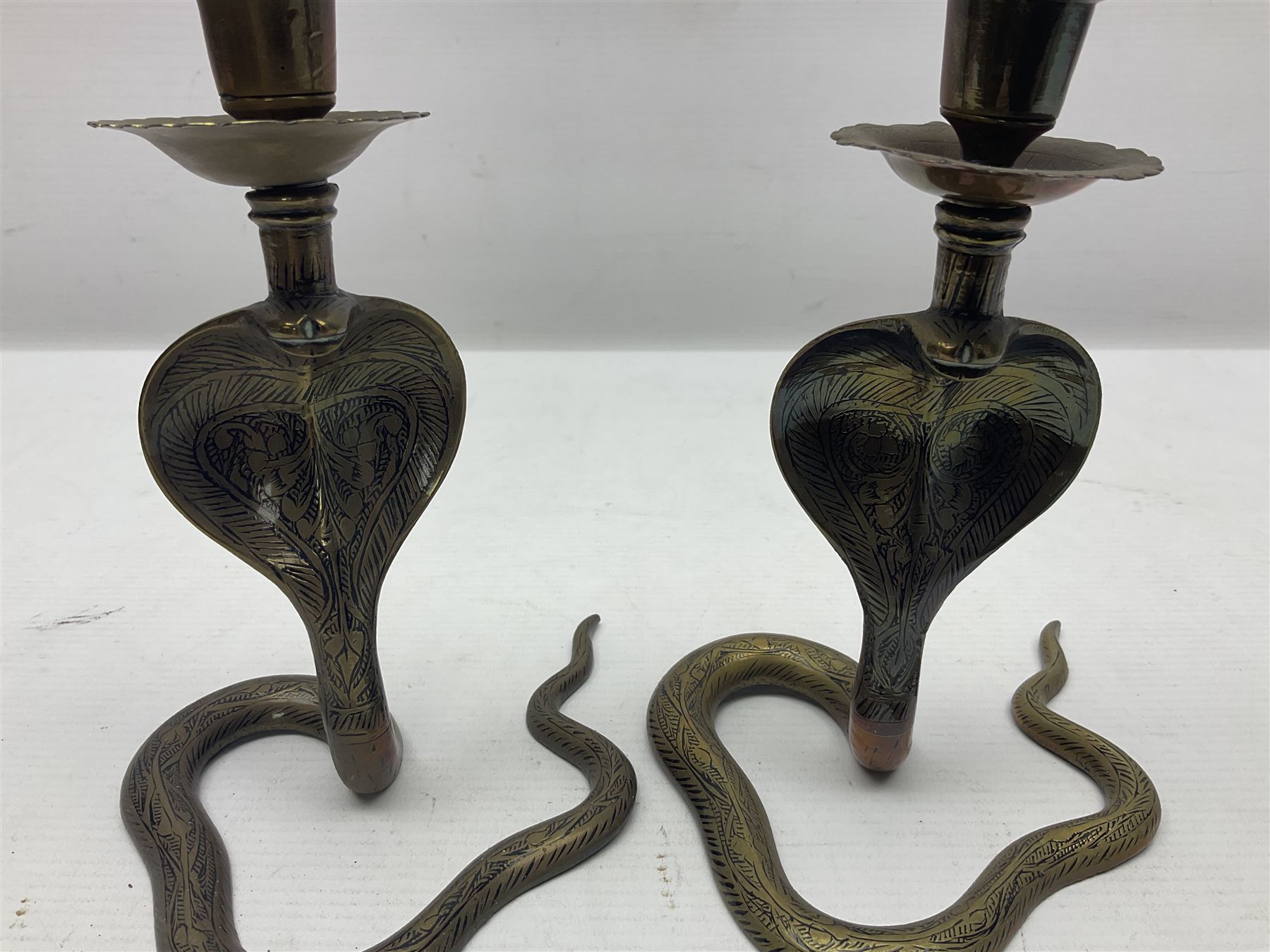 Indian brass pedestal dish, the dish engraved with peacock to centre, the stem modelled as a King Cobra, with engraved and enamelled decoration throughout, together with a similar pair of candlesticks, modelled as King Cobras, dish H23.5cm 