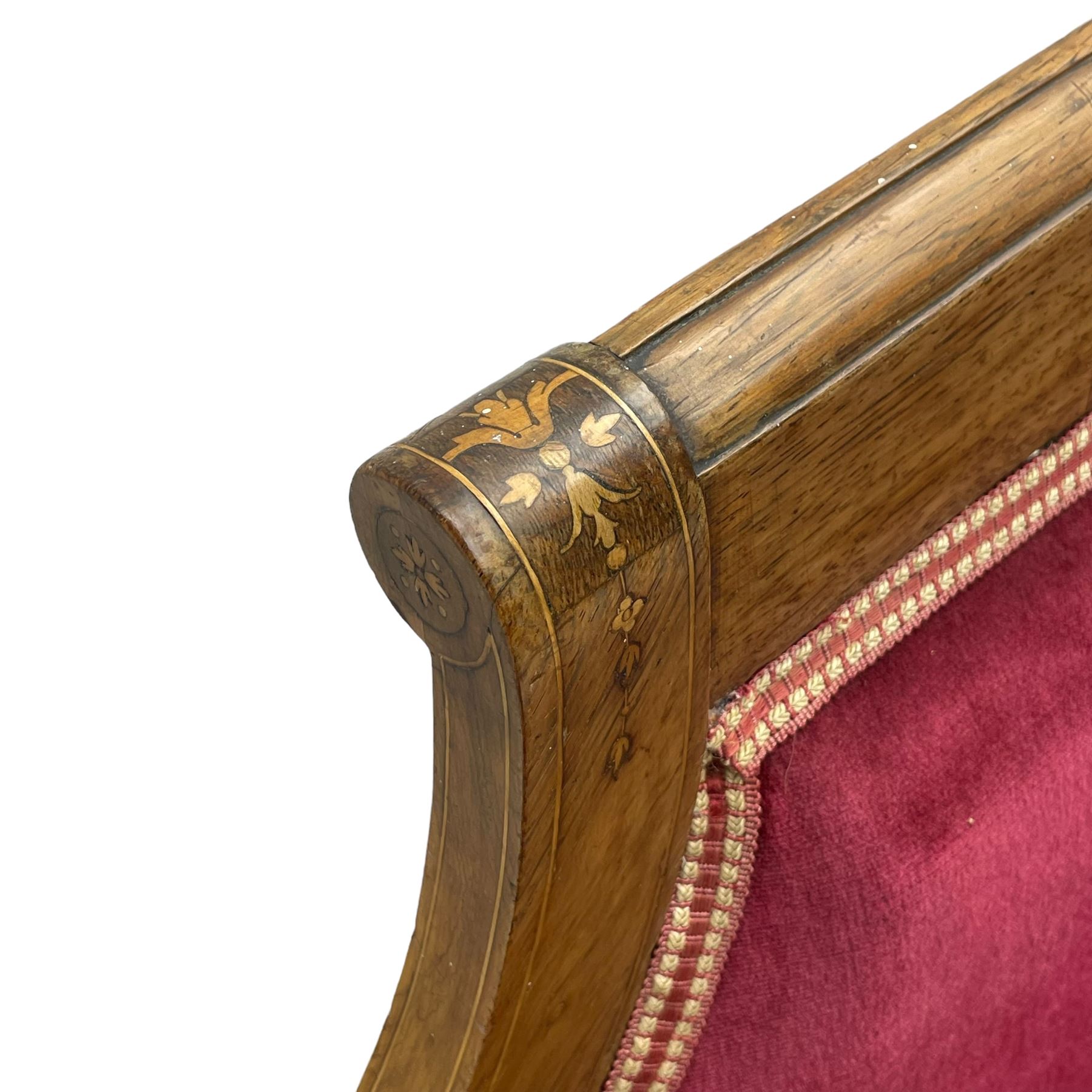 Late Victorian inlaid walnut two seat settee, the shaped cresting rail decorated with foliate inlays and boxwood stringing, upholstered in crimson velvet with sprung seat, raised on turned and fluted supports with ceramic castors