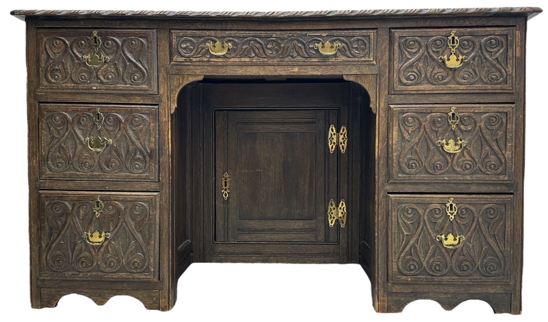 Victorian carved oak kneehole desk, the rectangular top with carved edge, above central drawer with carved front and brass handles, central kneehole with cupboard door, flanked by two banks of three graduating drawers each with similarly carved decoration, on shaped plinth base with castors