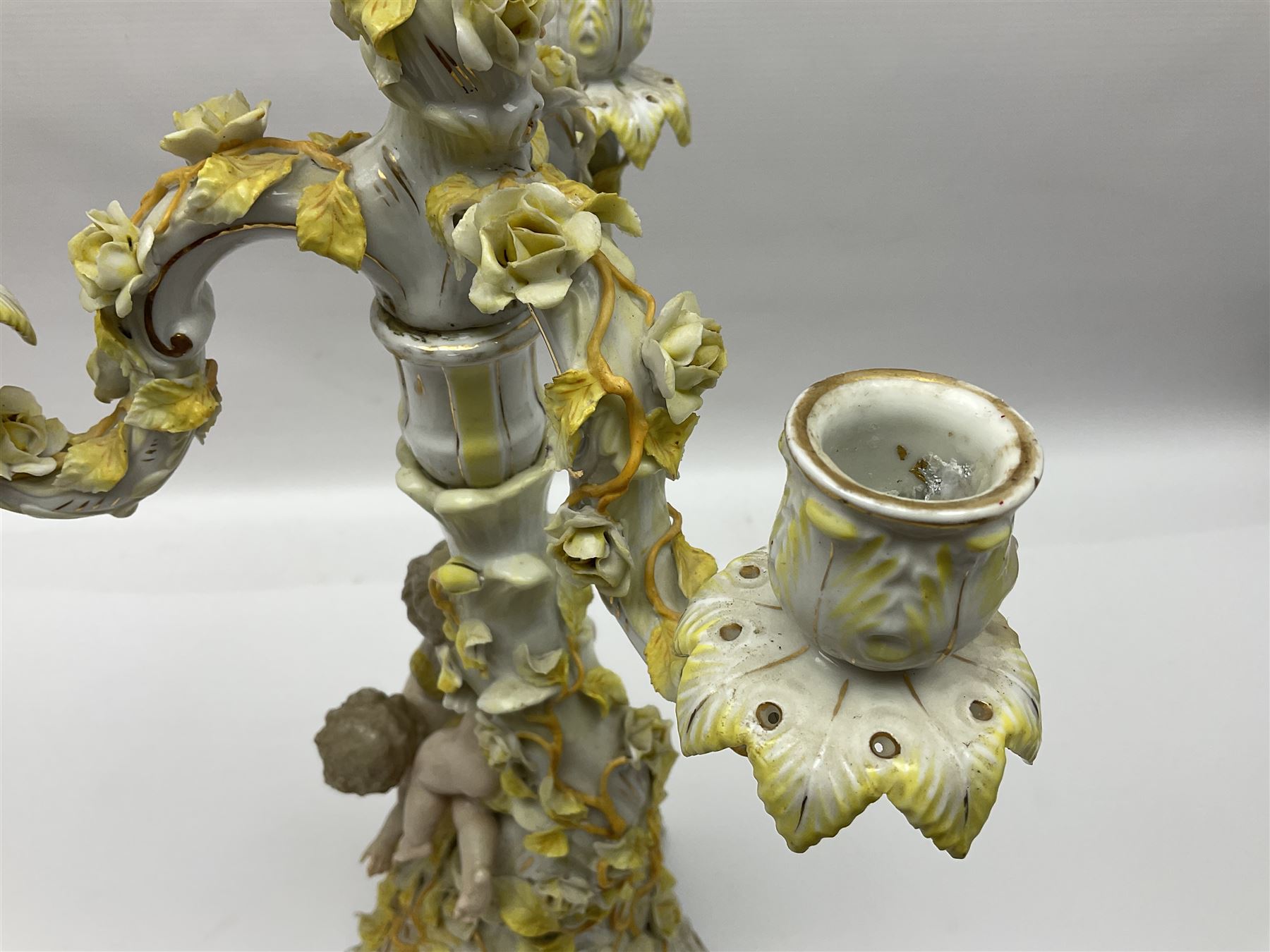 Dresden style candelabra, the central stem bordered by three branches, decorated with cherubs and yellow roses, H48cm