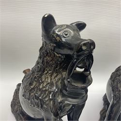 Pair of unusual early English pottery figures, modelled in the form of seated dogs with baskets between their jaws, the tails forming whistles, each upon rectangular base, overall H22cm