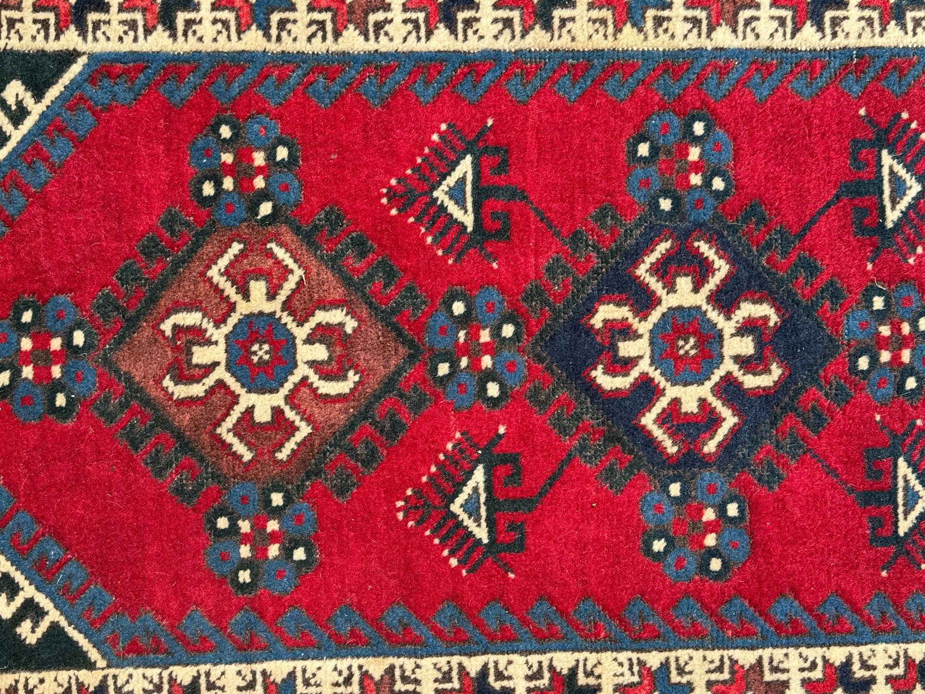 Turkish crimson ground rug, the field decorated with three geometric medallions within a band of star motifs, the main border decorated with stylised plant motifs 