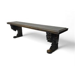 Victorian oak bench, moulded rectangular top, on mask and scroll carved corbel supports with paw feet, rectangular platforms with rounded terminals and applied roundel 