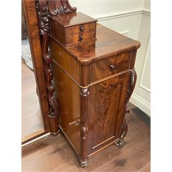 Tall Victorian figured mahogany twin pedestal dressing table, the tall mirror with flower head and scrolled leaf carved pediment, flanked by two turned and carved finials over faceted lancet arched lantern tops, plane mirror plate enclosed by shaped frame, pierced and undulating moulded uprights, on C-scroll and curled leaf carved supports fitted with cast brass hinged candle sconces, each pedestal fitted with two small trinket drawers over larger drawer and panelled cupboard, canted corners with matched upright mounts, the cupboard doors enclosing slides, on scroll carved feet 