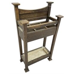 Early 20th century Arts & Crafts oak stick stand, panelled back over three divisions, fitted with metal drip tray, on square supports