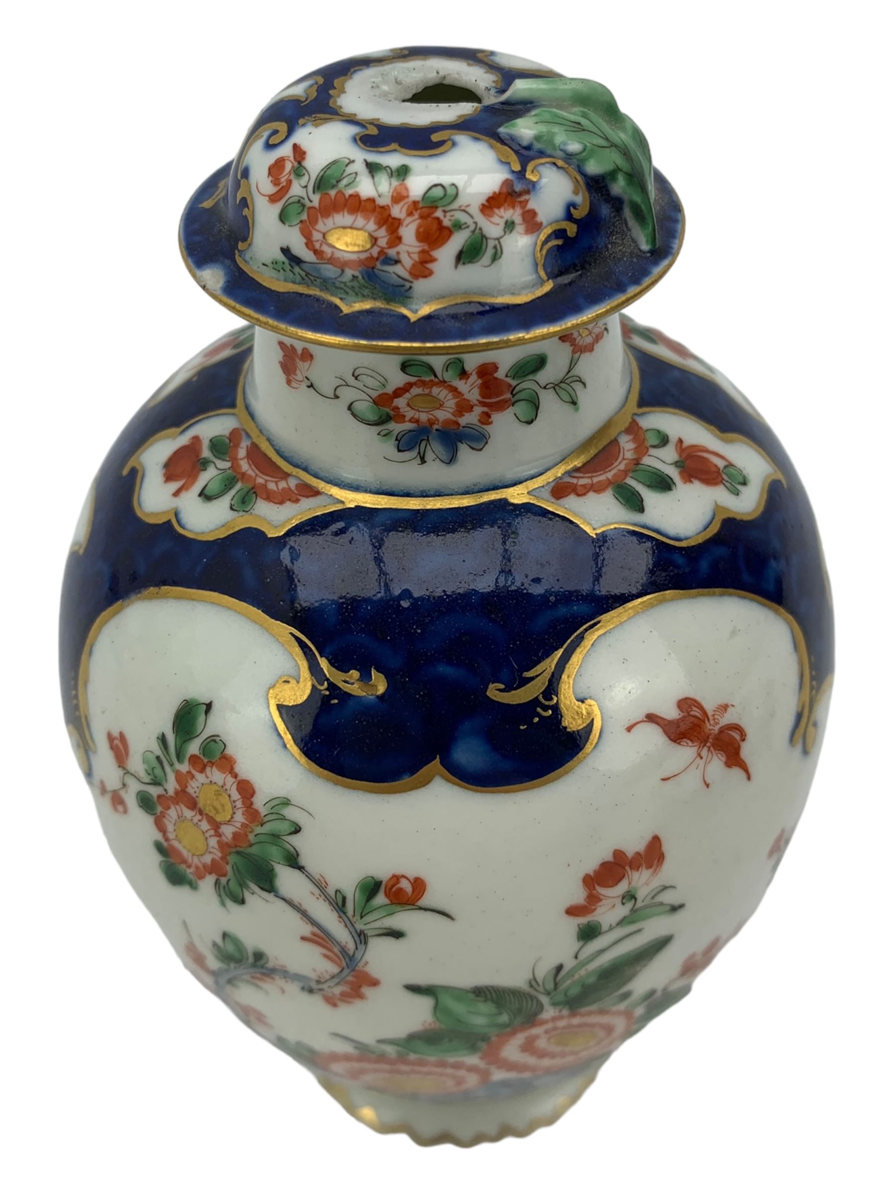 18th century Worcester tea caddy, of oval form and painted in the Kakiemon palette with reserves of flowers against a blue scale ground, H14cm together with a similar Worcester circular dish, painted with floral sprays, within a scalloped edge, blue crescent mark beneath, D19cm (2)