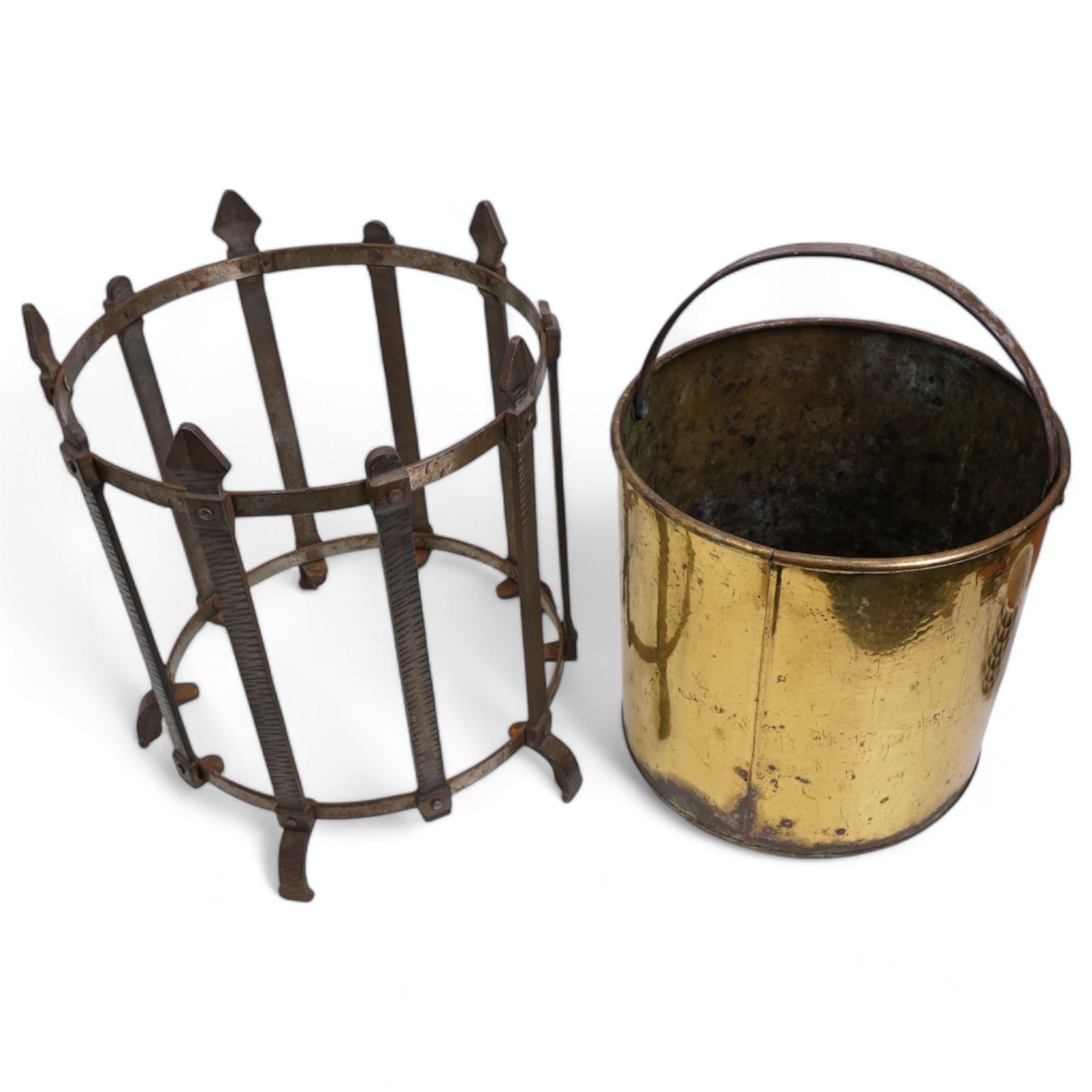 19th/ early 20th century wrought iron and brass coal bucket, of cylindrical form with gothic iron frame, upon five shaped supports, H36.5cm, together with a Georgian wrought iron and pierced brass trivet, with turned elm handle (2)