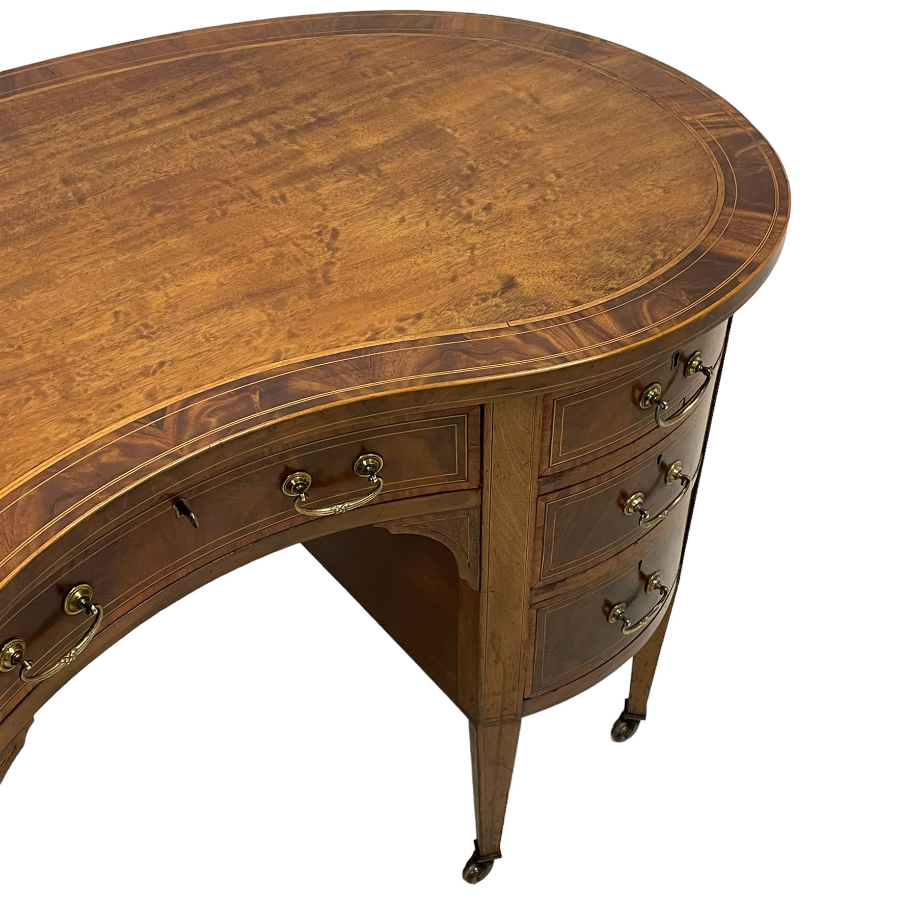 Edwardian mahogany and satinwood banded kidney-shaped writing desk, the shaped top with figured mahogany banding and boxwood stringing, fitted with seven drawers with satinwood bandings, on square tapering supports with brass and ceramic castors