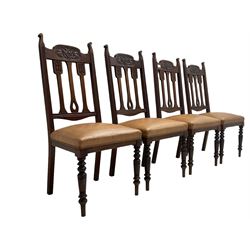 Set of four Edwardian walnut dining chairs, foliate carved high back over sprung seat upholstered in tan faux leather, raised on turned supports