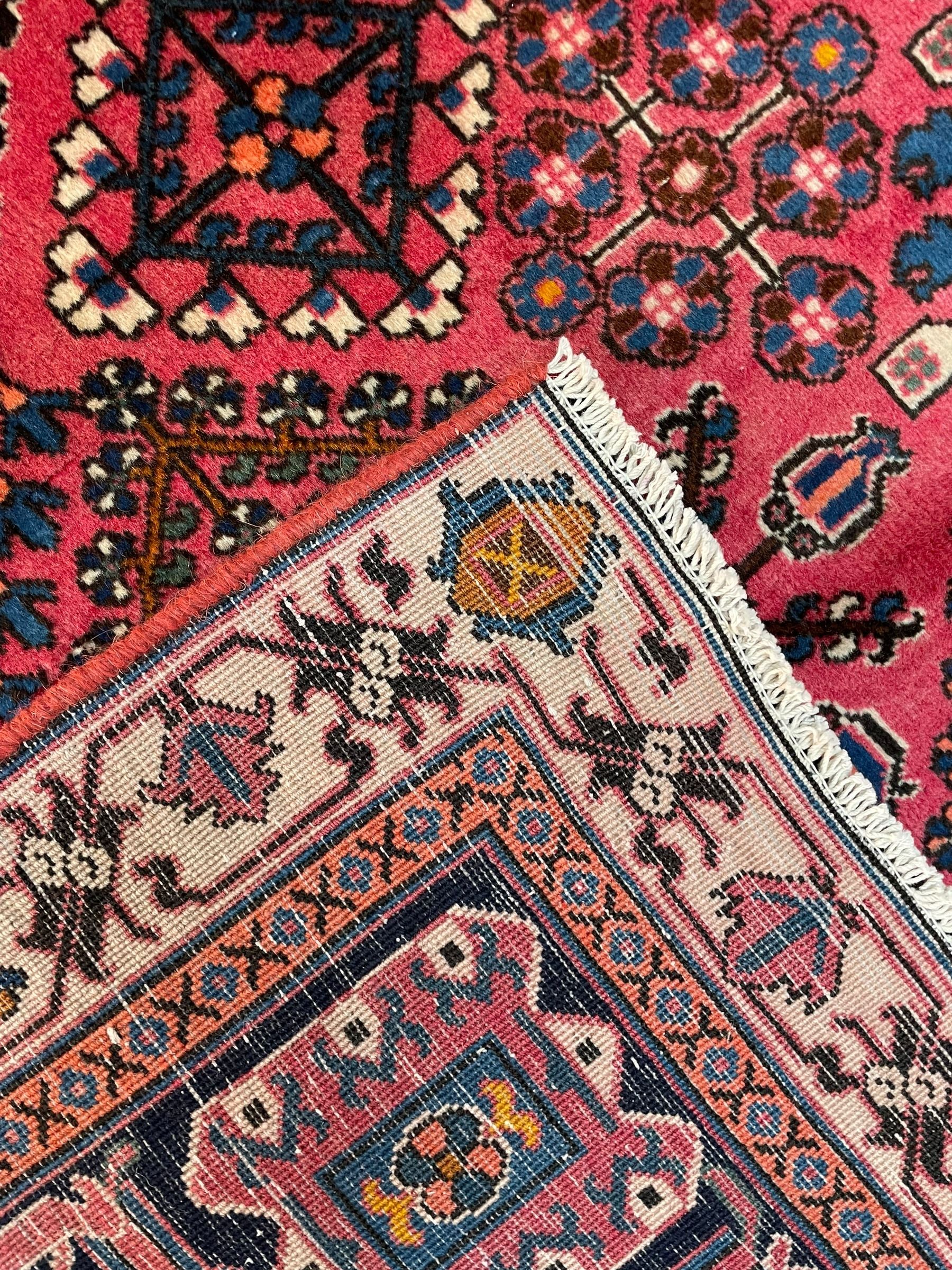 Persian Joshaghan red ground rug, the medallion, field and spandrels decorated with Pitrak and tree of life motifs, the border with repeating design decorated with stylised plant motifs, within guard stripes