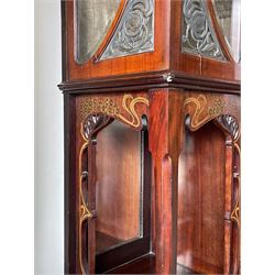 Art Nouveau period inlaid mahogany display cabinet, raised shaped and moulded pediment over projecting moulded cornices, the upper frieze inlaid with trailing branches and tulips, single astragal and bevel glazed door enclosed velvet lined interior fitted with shelves, flanked by curved glass panes decorated with pierced metal foliate spandrels, lower flanking shelves with mirror backs enclosed within shaped and pierced rails inlaid with flower heads, on tapering octagonal supports terminating to compressed pad feet, the lock stamped 'Salmon Bros, London' 