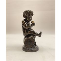 Bronzed metal model of a putti seated upon a barrel with goblet in hands, and fruiting vines adorning their head, H17.5cm