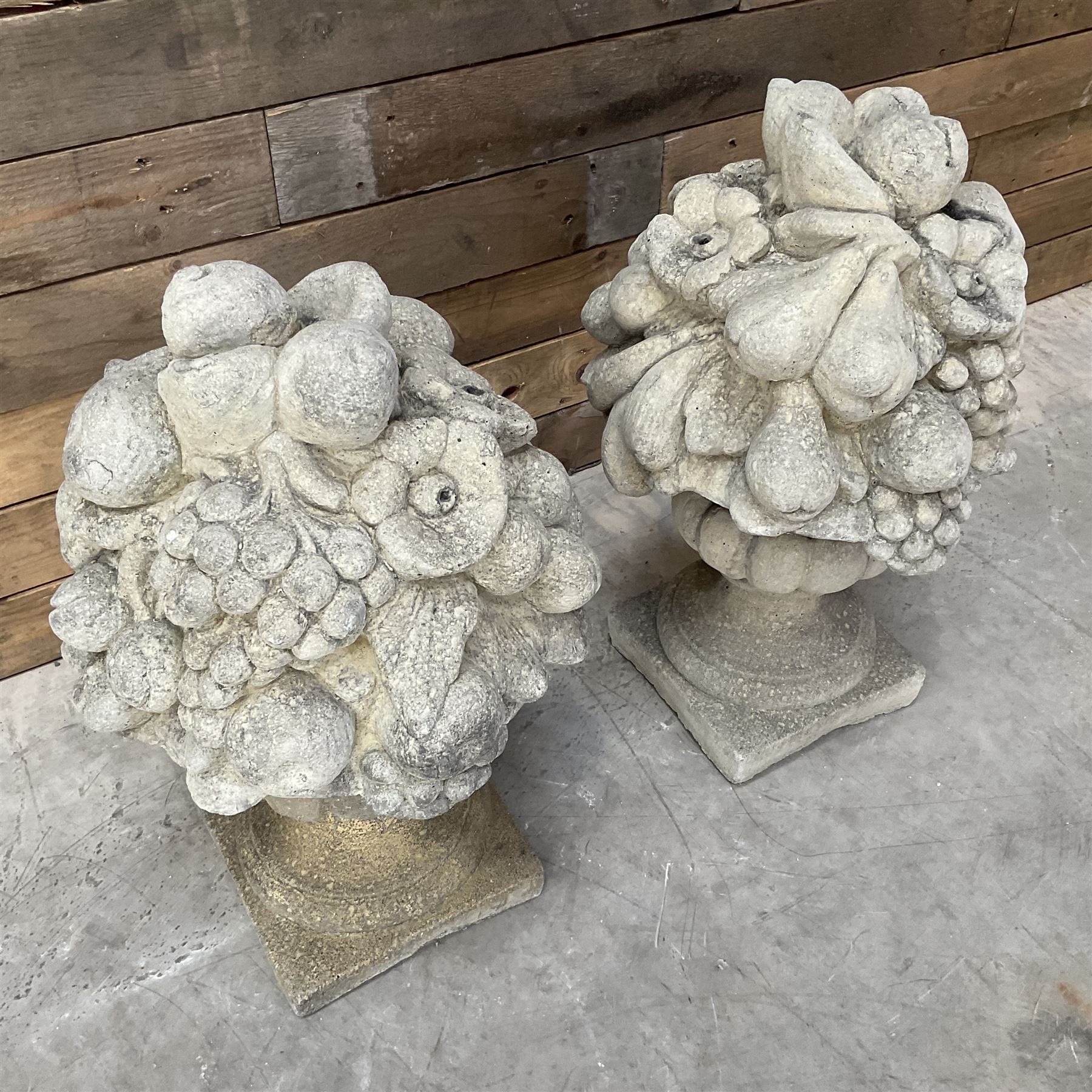 Pair of cast stone garden wall or gate finials depicting Fruit Piers, raised on separate circular squat column with plinth base