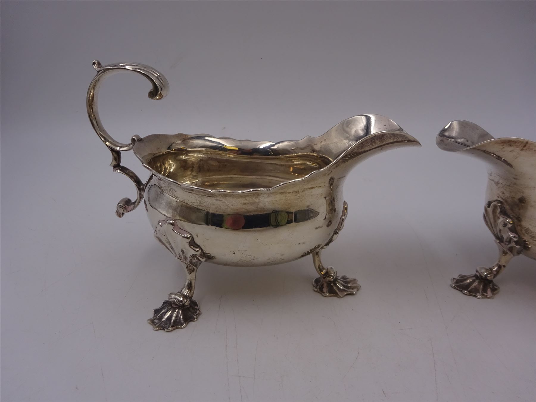 Near pair of George II silver sauce boats, each of oval form with shaped rim and capped flying scroll handle, upon three scroll mounted feet, hallmarked David Hennell, London 1758, H12cm