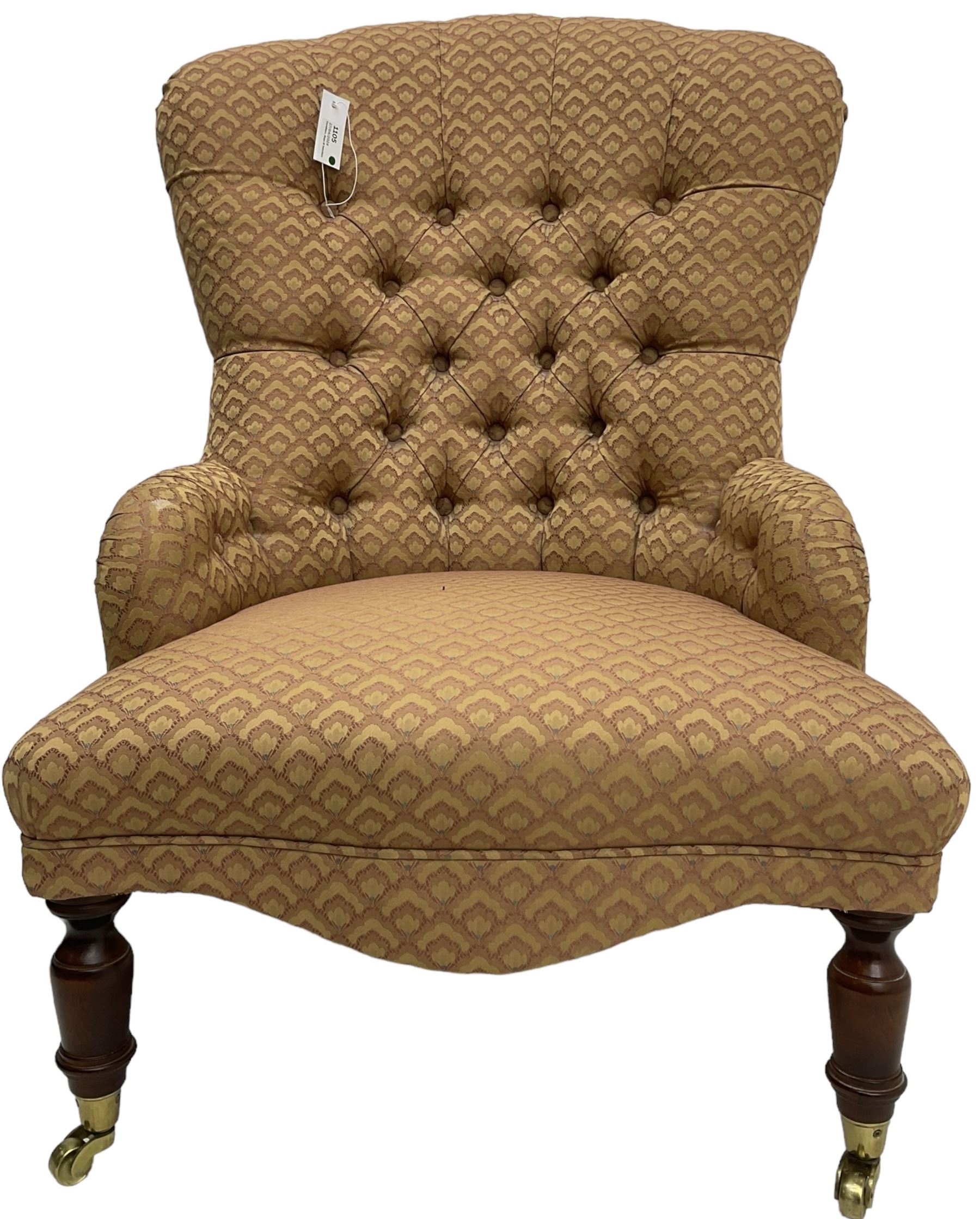 Victorian design armchair, buttoned back and spring seat upholstered in red and gold patterned fabric, shaped apron over turned mahogany supports with brass cups and castors