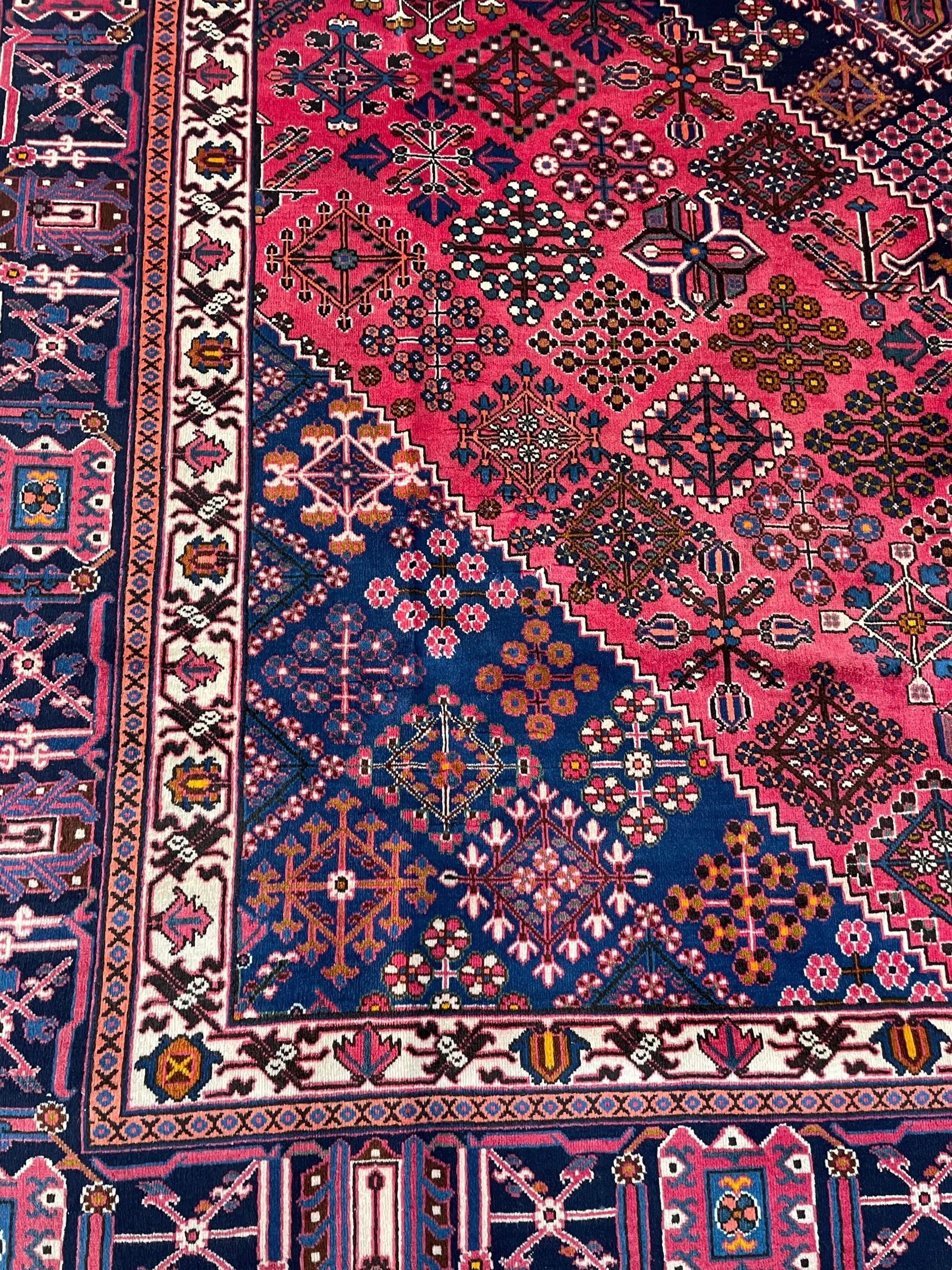 Persian Joshaghan red ground rug, the medallion, field and spandrels decorated with Pitrak and tree of life motifs, the border with repeating design decorated with stylised plant motifs, within guard stripes