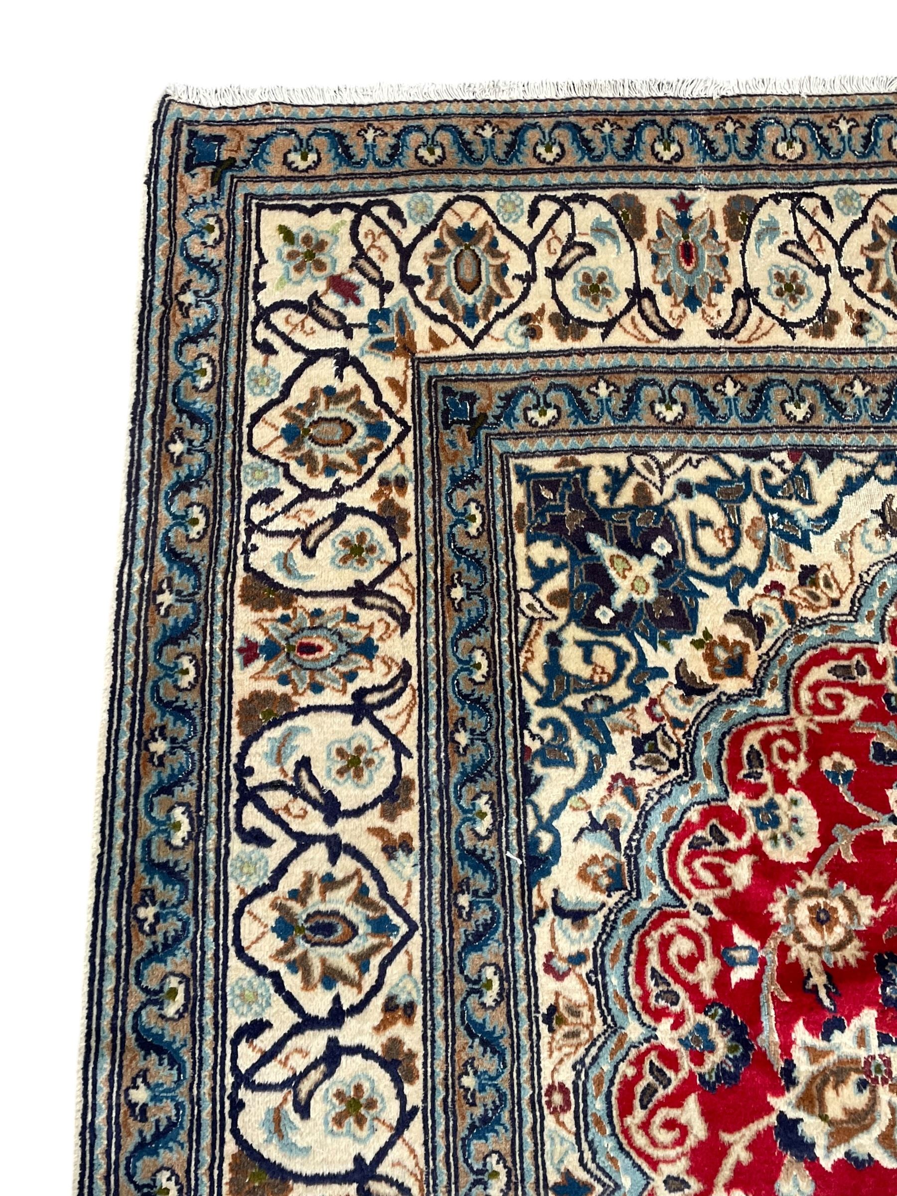 Persian Kashan crimson rug, central cusped medallion surrounded by interlacing branches decorated with leaves and palmettes, ivory ground spandrels and border decorated with scrolling branches and stylised plant motifs, within guard stripes  