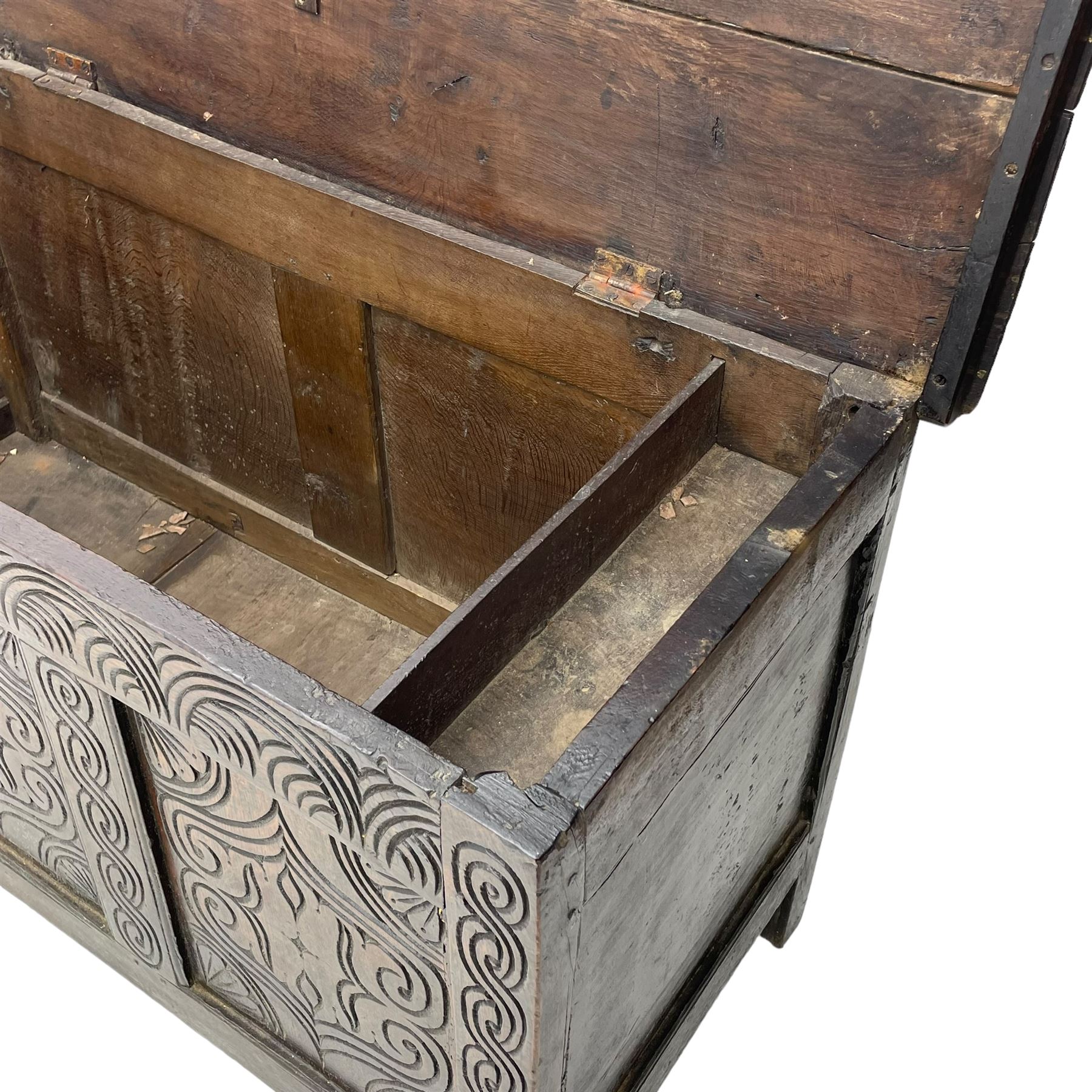 18th century oak blanket box, moulded and chip carved hinged lid, lunette carved cresting rail over triple panelled front carved with stylised leaf and scroll decoration, interlocking S-scroll carved upright rails, panelled sides and back, on stile supports 