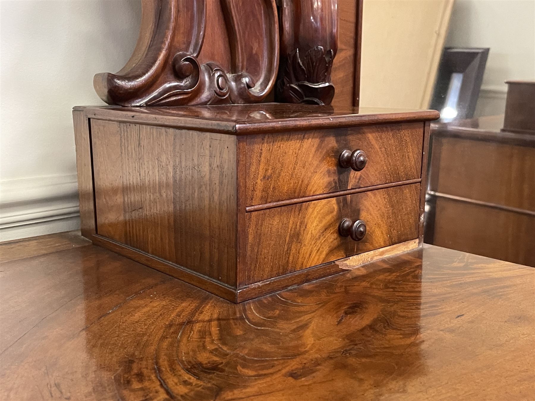 Tall Victorian figured mahogany twin pedestal dressing table, the tall mirror with flower head and scrolled leaf carved pediment, flanked by two turned and carved finials over faceted lancet arched lantern tops, plane mirror plate enclosed by shaped frame, pierced and undulating moulded uprights, on C-scroll and curled leaf carved supports fitted with cast brass hinged candle sconces, each pedestal fitted with two small trinket drawers over larger drawer and panelled cupboard, canted corners with matched upright mounts, the cupboard doors enclosing slides, on scroll carved feet 