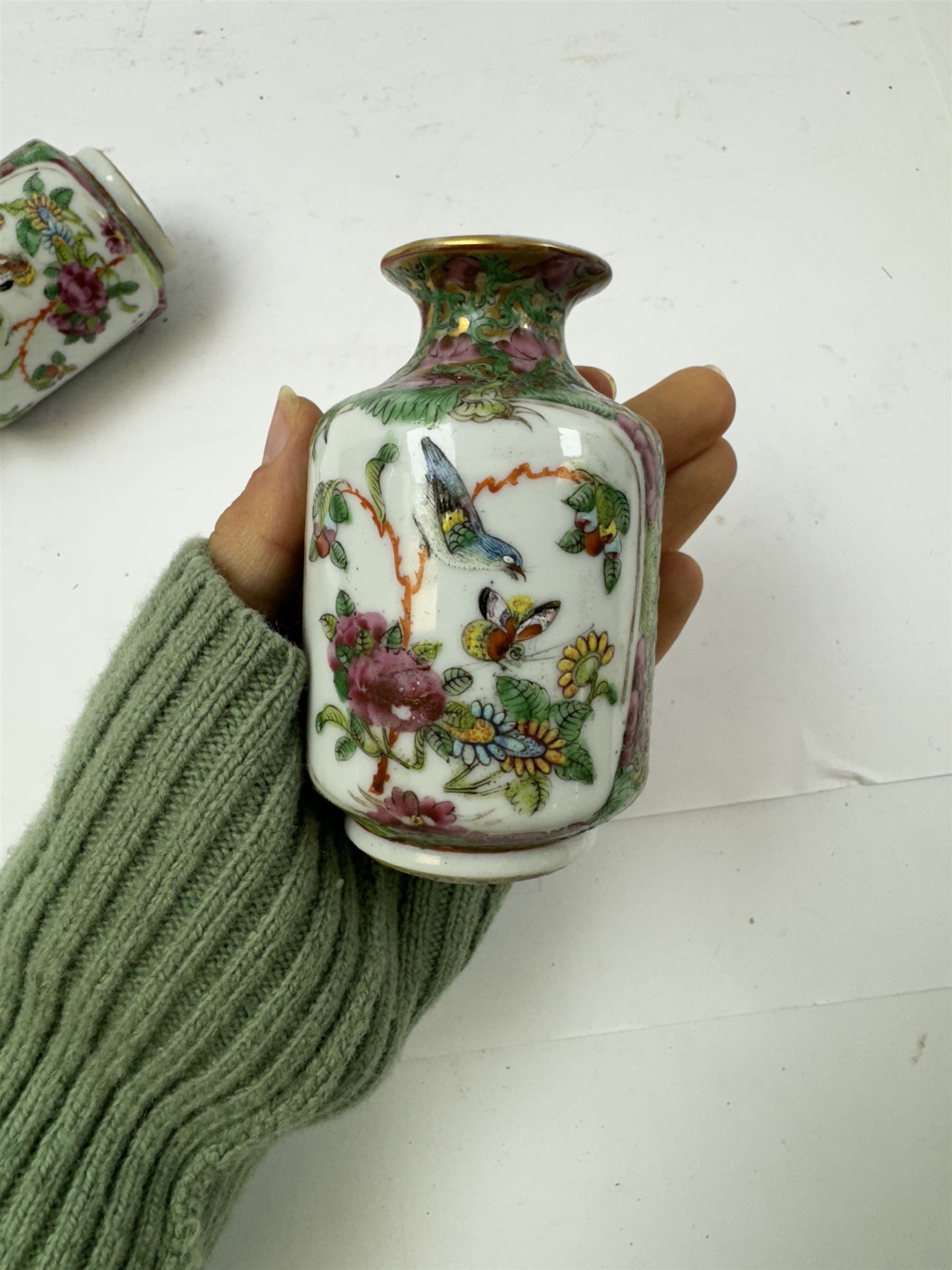 Pair of Chinese famille rose miniature vases, painted with panels depicting figures in a garden, with flora and fauna decoration, H10cm