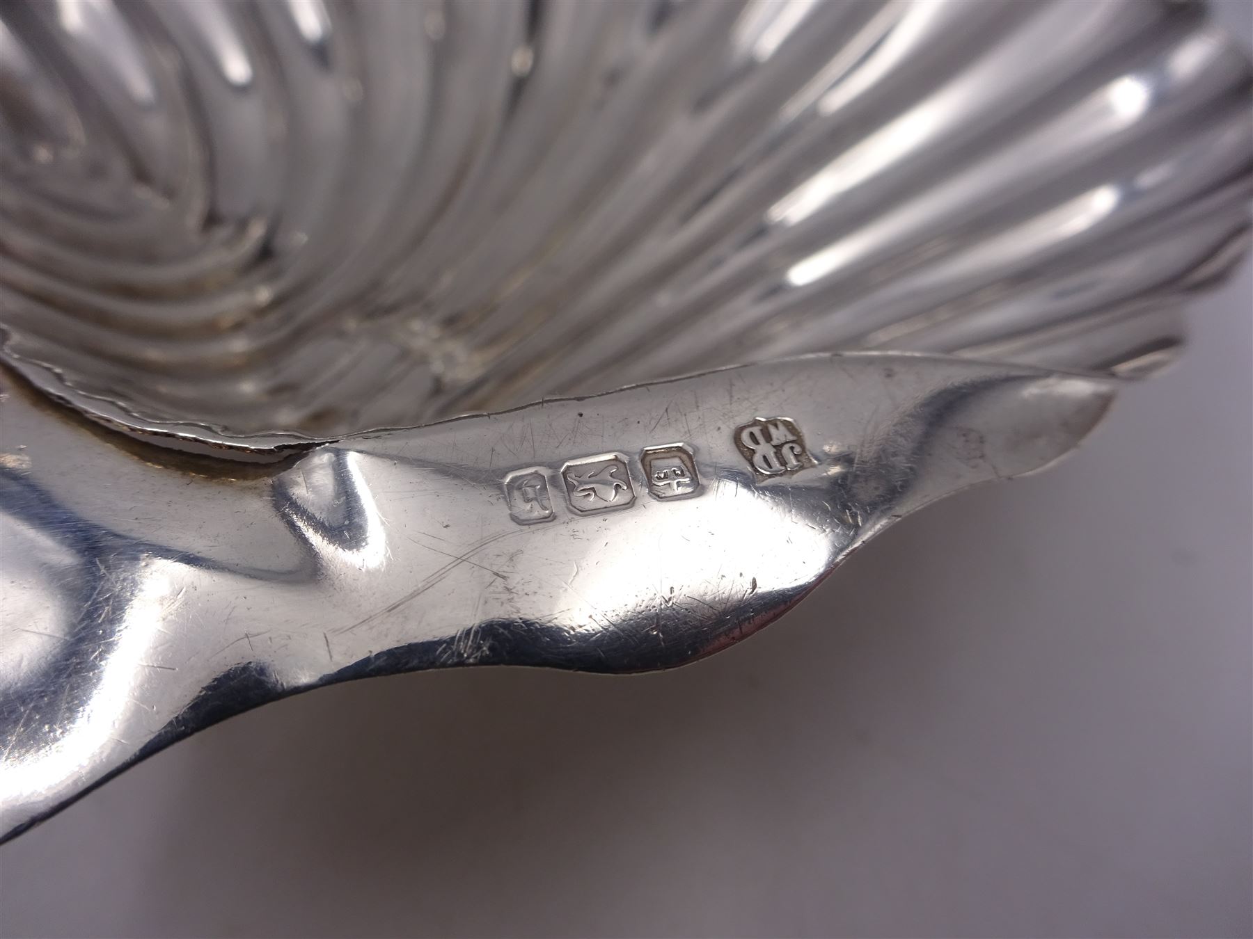 Pair of late Victorian silver shell butter dishes, upon three bun feet, hallmarked James Deakin & Sons, Sheffield 1900, together with a pair of late Victorian scissor action sugar nips, engraved with foliate decoration, hallmarked Sheffield 1897, maker's mark indistinct