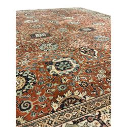 Persian design carpet, rust ground field decorated with large stylised plant motifs surrounded by smaller floral motifs, repeating trailing border