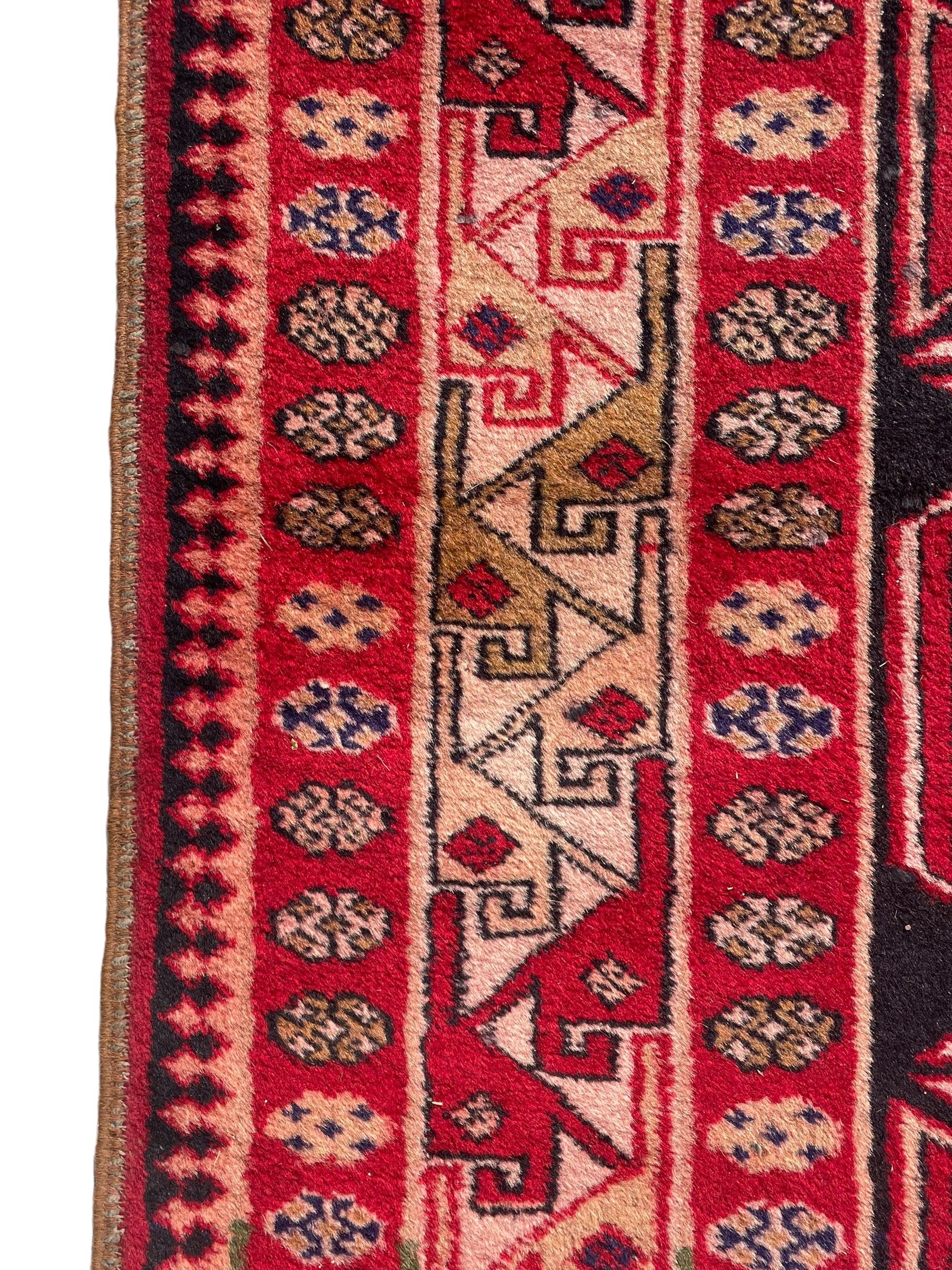 Persian Hamadan indigo and crimson ground rug, the field filled with three shaped medallions, overall geometric design, decorated with sandikli and hac motifs, geometric main border with repeating hooked motifs, within guard stripes decorated with small flower heads, outer crenelated fence band 