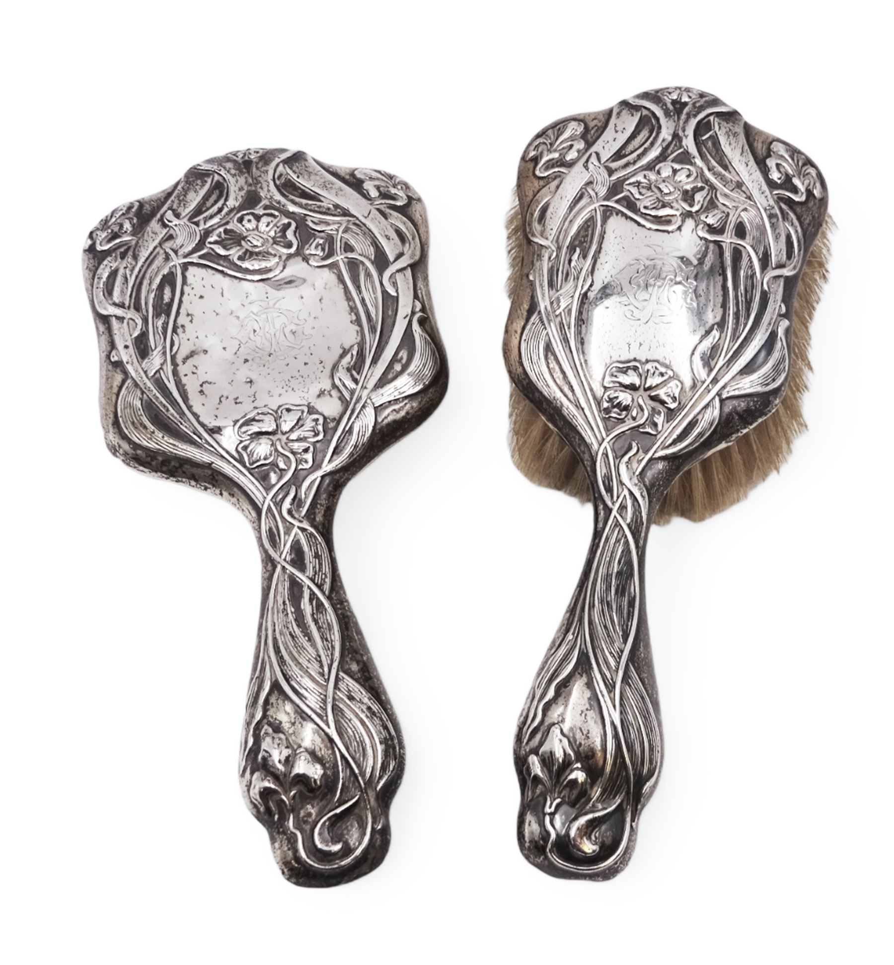 Art Nouveau silver mounted two piece dressing table set, comprising hair brush and hand mirror, each heavily embossed with naturlistic florals and engrved with monograms, hallmarked Walker & Hall, Sheffield 1907