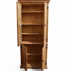 Tall 20th century stained pine cupboard, projecting cornice over four panelled cupboard doors, enclosing shelves, on skirted base, with iron fittings and handles