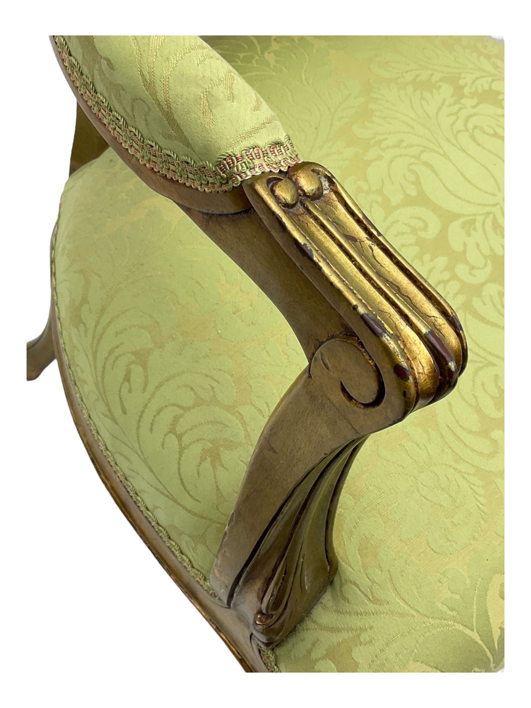 Late 20th century French design gilt framed armchair, upholstered in lime green damask fabric, arched back with carved crest, scroll arms, serpentine front rail, on cabriole front supports with ball feet