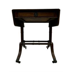 Mahogany drop-leaf sofa table, rectangular top over single frieze drawer with carved rosette handle, twin turned columns united by twin stretchers, on splayed supports terminating in paw feet with castors