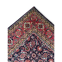 Persian Farahan indigo ground rug, the field decorated with large repeating floral herati motifs, crimson ground border decorated with palmettes and trailing leafy branch, within guard stripes 