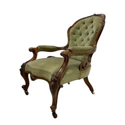 Pair of lady's and gentleman's Victorian carved walnut armchair and nursing chair, foliate carved cresting rail over shaped back with scrolled acanthus carved sides, the armchair with scroll arm terminals, the spoon back and sprung seat upholstered in buttoned sage green velvet, raised on cabriole supports with bell-flower moulded knees and scroll feet, on ceramic castors