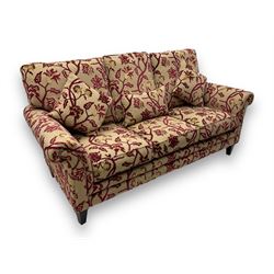 Contemporary upholstered three-seat sofa, scroll arms and loose cushions, embossed beige ground fabric with red and gold floral motifs, on tapered wooden supports