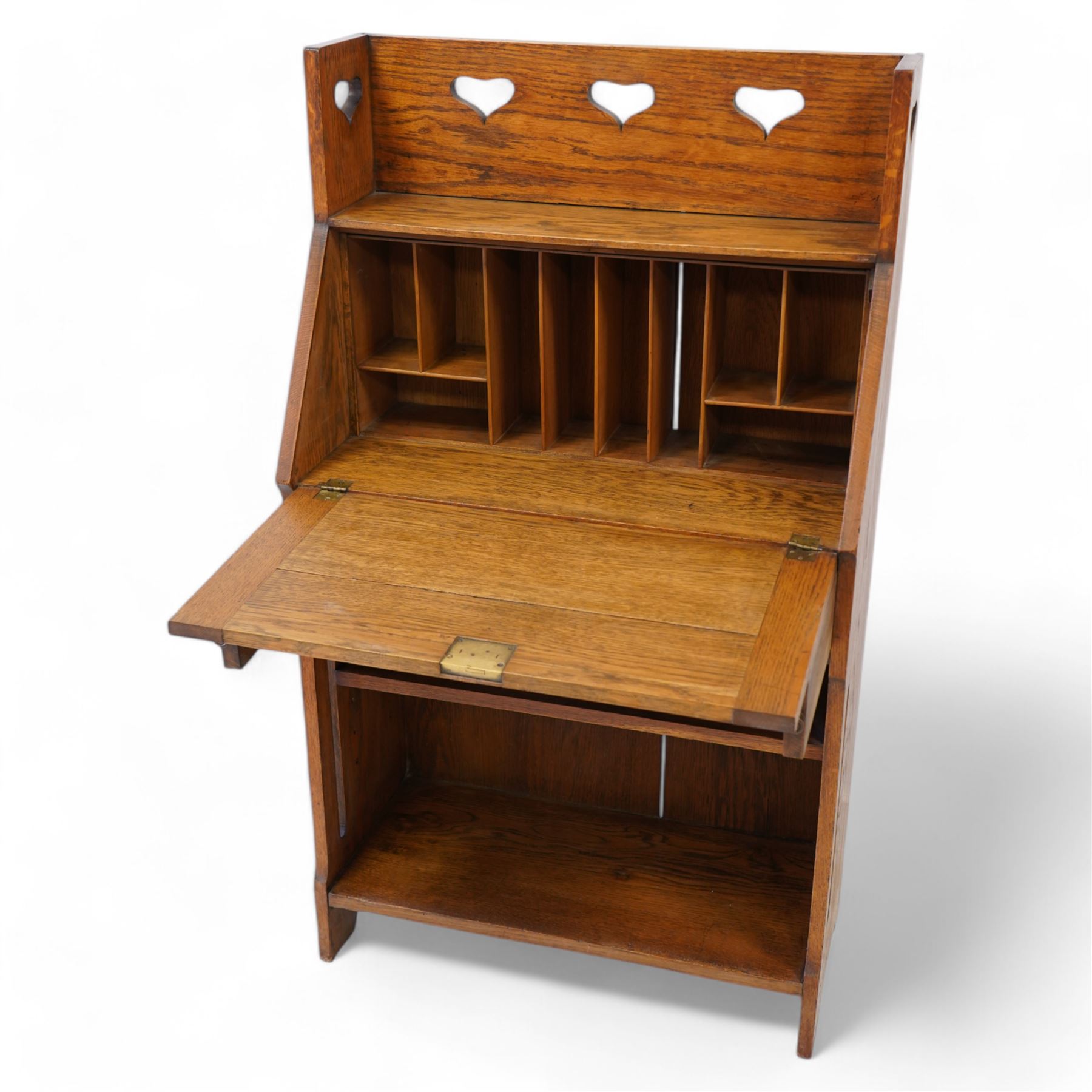 Possibly Liberty & Co - Arts & Crafts light oak bureau, the three-quarter raised gallery pierced with hearts, over a fall-front enclosing fitted interior with correspondence and pigeonholes, fitted with single drawer with poppy decorated handles, single open shelf to base