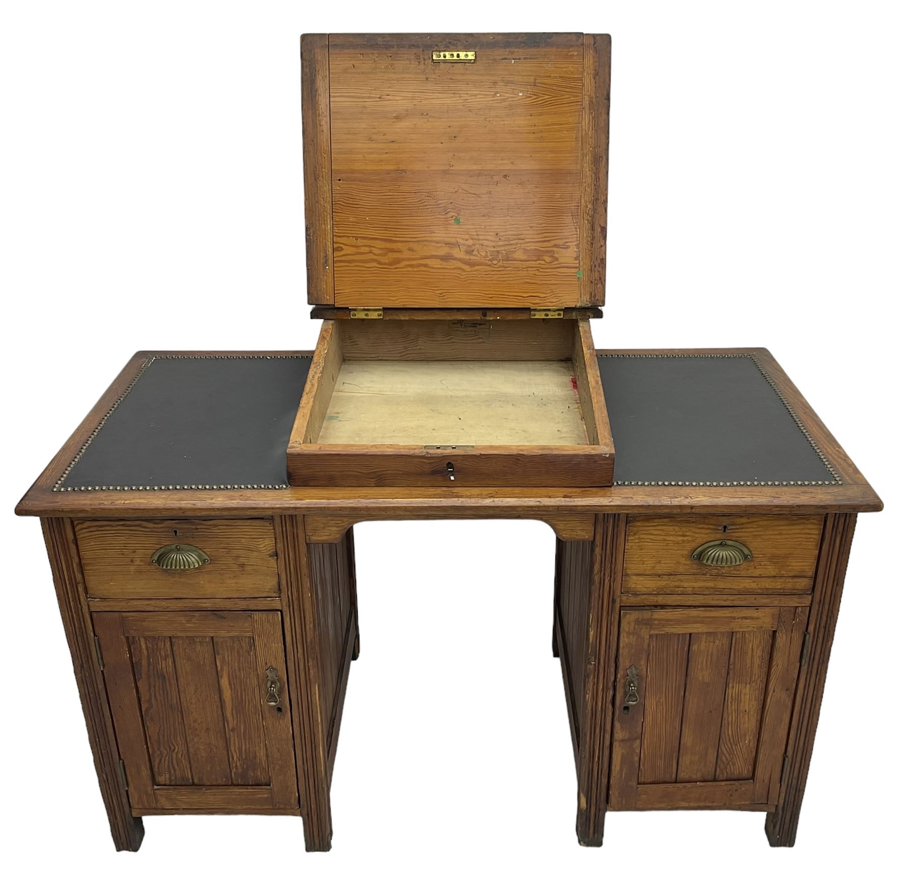 Edwardian pitch pine desk, rectangular top with writing slope flanked by inset leather writing surfaces, over twin pedestals each with shell cup handled drawer over cupboard, the left enclosing two shelves, the right enclosing sliding trays, on fluted straight supports