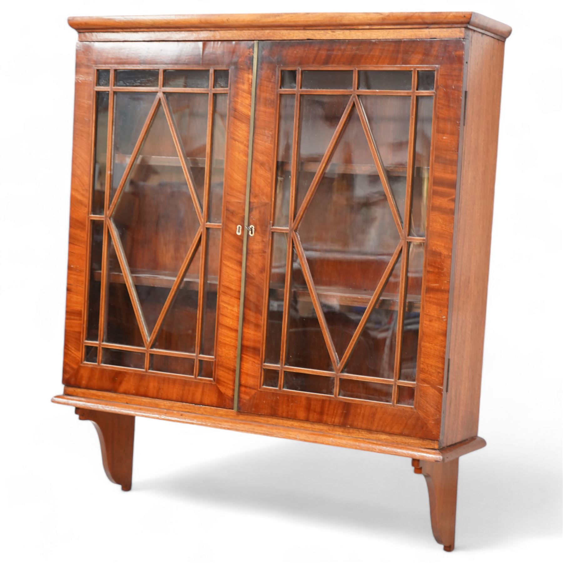 Edwardian inlaid mahogany wall-hanging cabinet, fitted with two astragal glazed doors enclosing two shelves, over shaped brackets