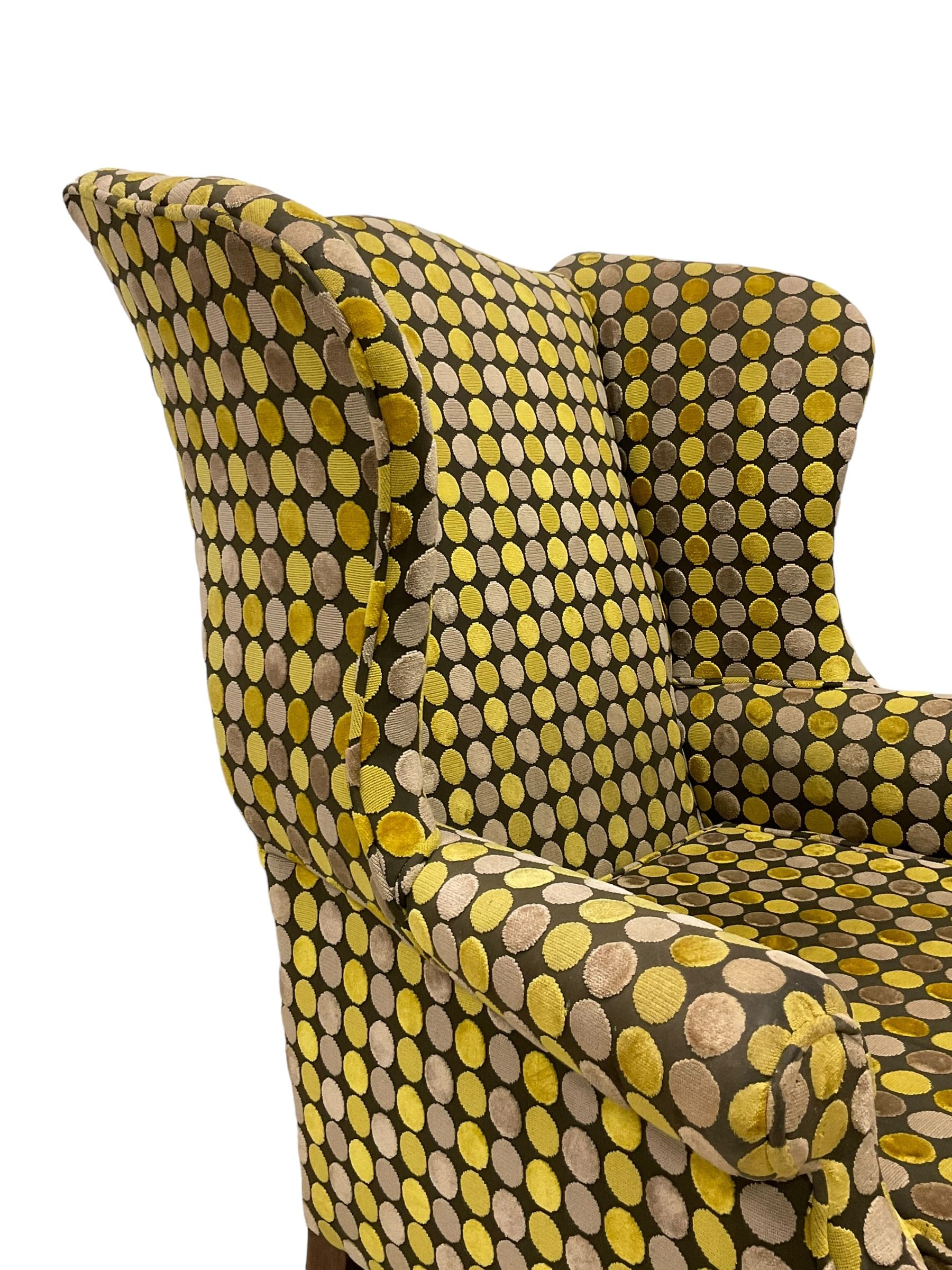 Georgian design mahogany framed wingback armchair, upholstered in spotted fabric in shades of grey and green, on moulded square supports united by stretchers 