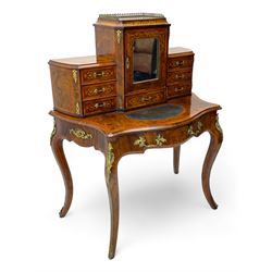 19th century French figured walnut Bonheur de Jour or writing desk, the upper section with brass gallery over mirror glazed cupboard and a combination of drawers, shaped and moulded top with leather inset and satinwood band, fitted with single drawer, on cabriole supports, inlaid throughout with scrolling foliate decoration in boxwood, ornate cast brass mounts 