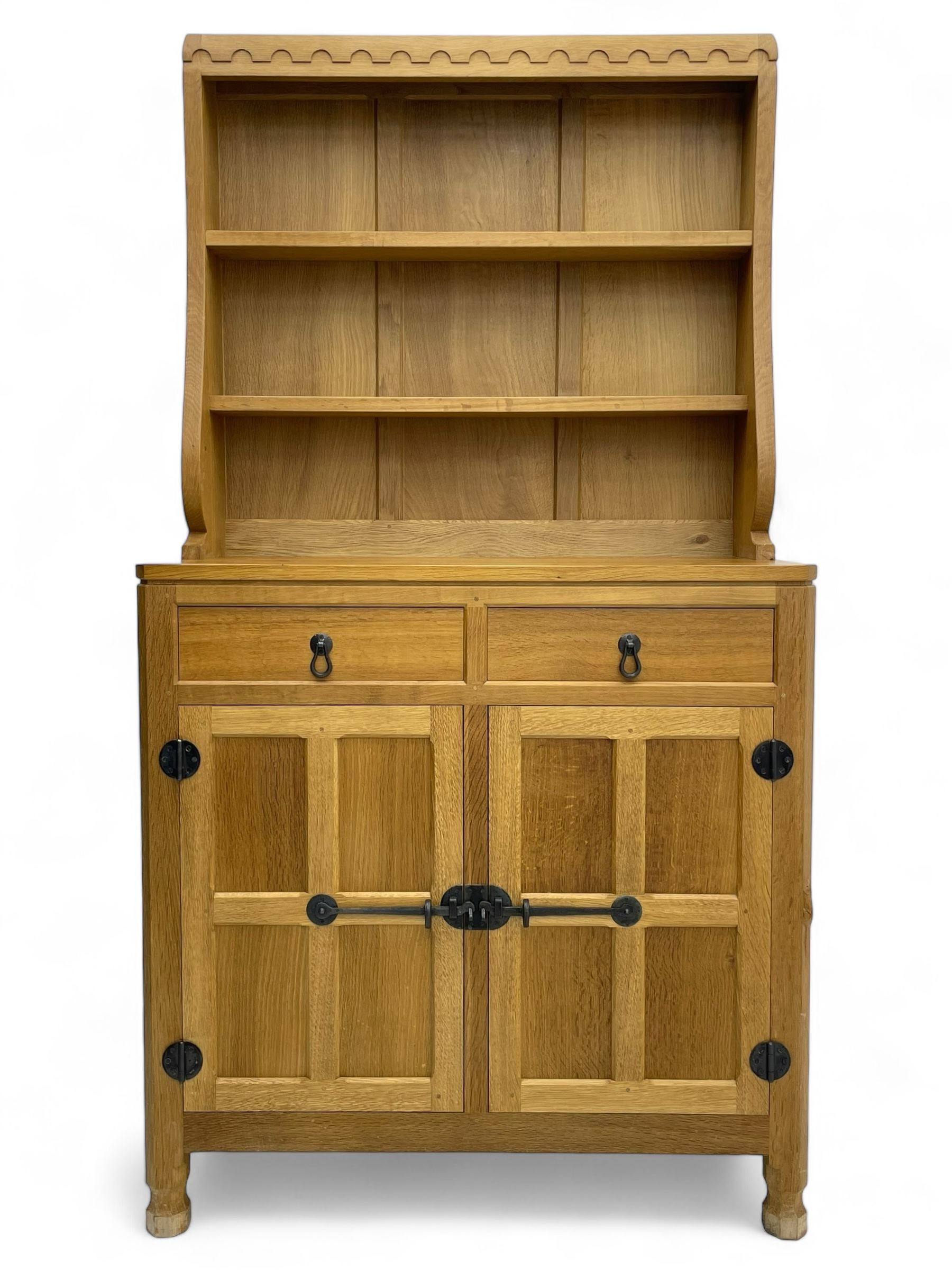 Mouseman - oak dresser, penny moulded cresting rail over two shelves supported by shaped ends, canted rectangular adzed top, fitted with two drawers and panelled cupboards, with wrought iron hinges and catches, on octagonal feet, carved with mouse signature, by the workshop of Robert Thompson, Kilburn 