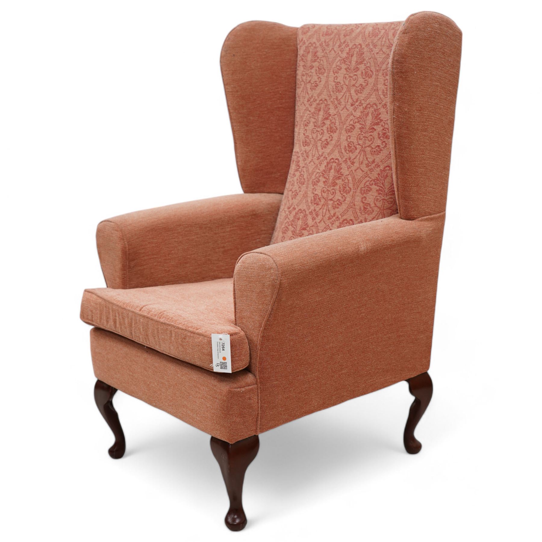 Hardwood-framed wingback armchair, upholstered in peach fabric, on cabriole feet 