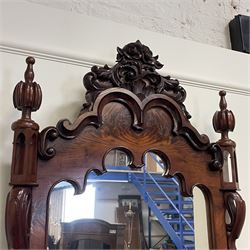 Tall Victorian figured mahogany twin pedestal dressing table, the tall mirror with flower head and scrolled leaf carved pediment, flanked by two turned and carved finials over faceted lancet arched lantern tops, plane mirror plate enclosed by shaped frame, pierced and undulating moulded uprights, on C-scroll and curled leaf carved supports fitted with cast brass hinged candle sconces, each pedestal fitted with two small trinket drawers over larger drawer and panelled cupboard, canted corners with matched upright mounts, the cupboard doors enclosing slides, on scroll carved feet 