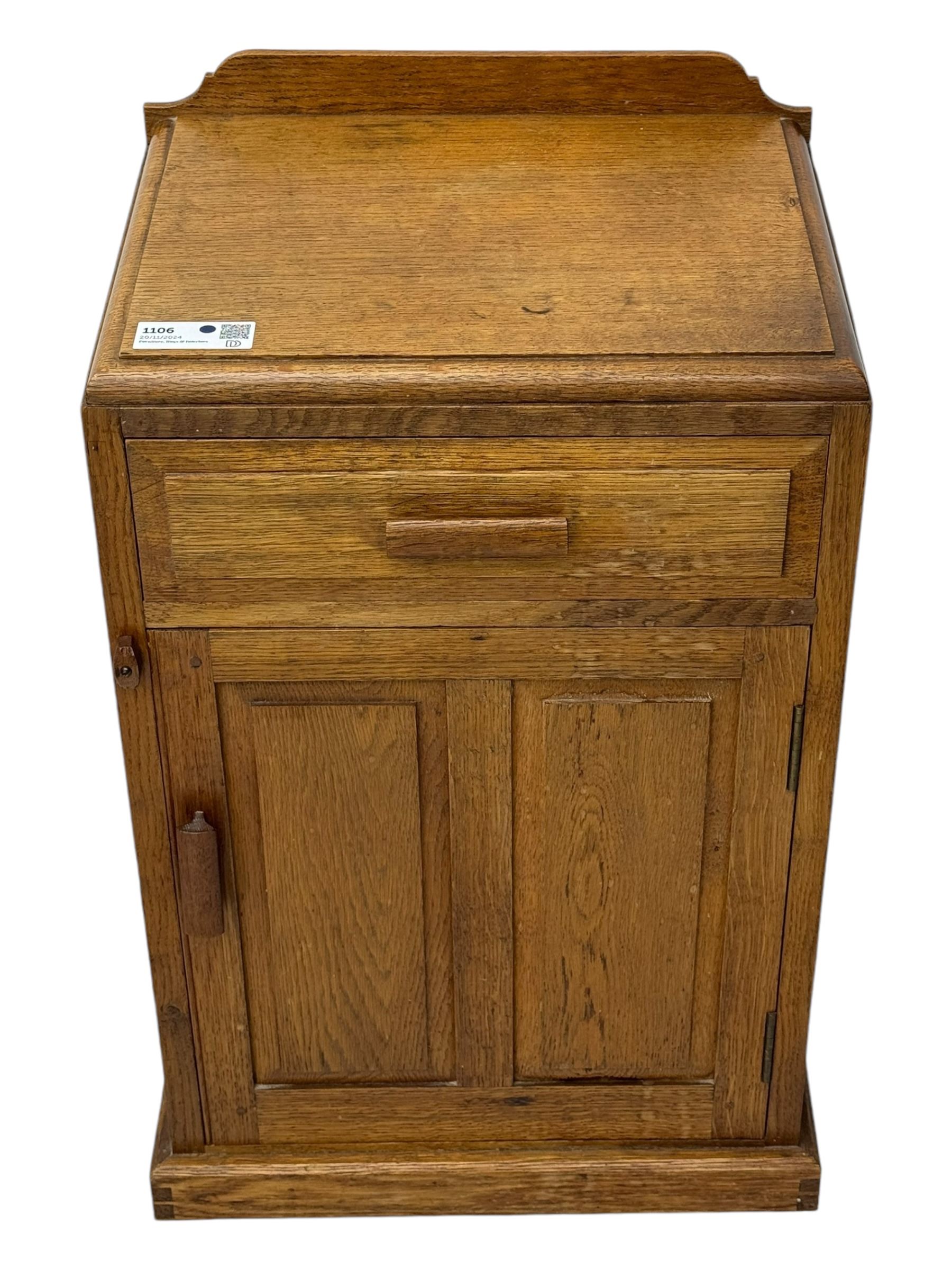 Arts & Crafts period oak bedside cupboard, raised back over moulded top, fitted with single drawer over panelled cupboard, panelled sides, on chamfered plinth base 