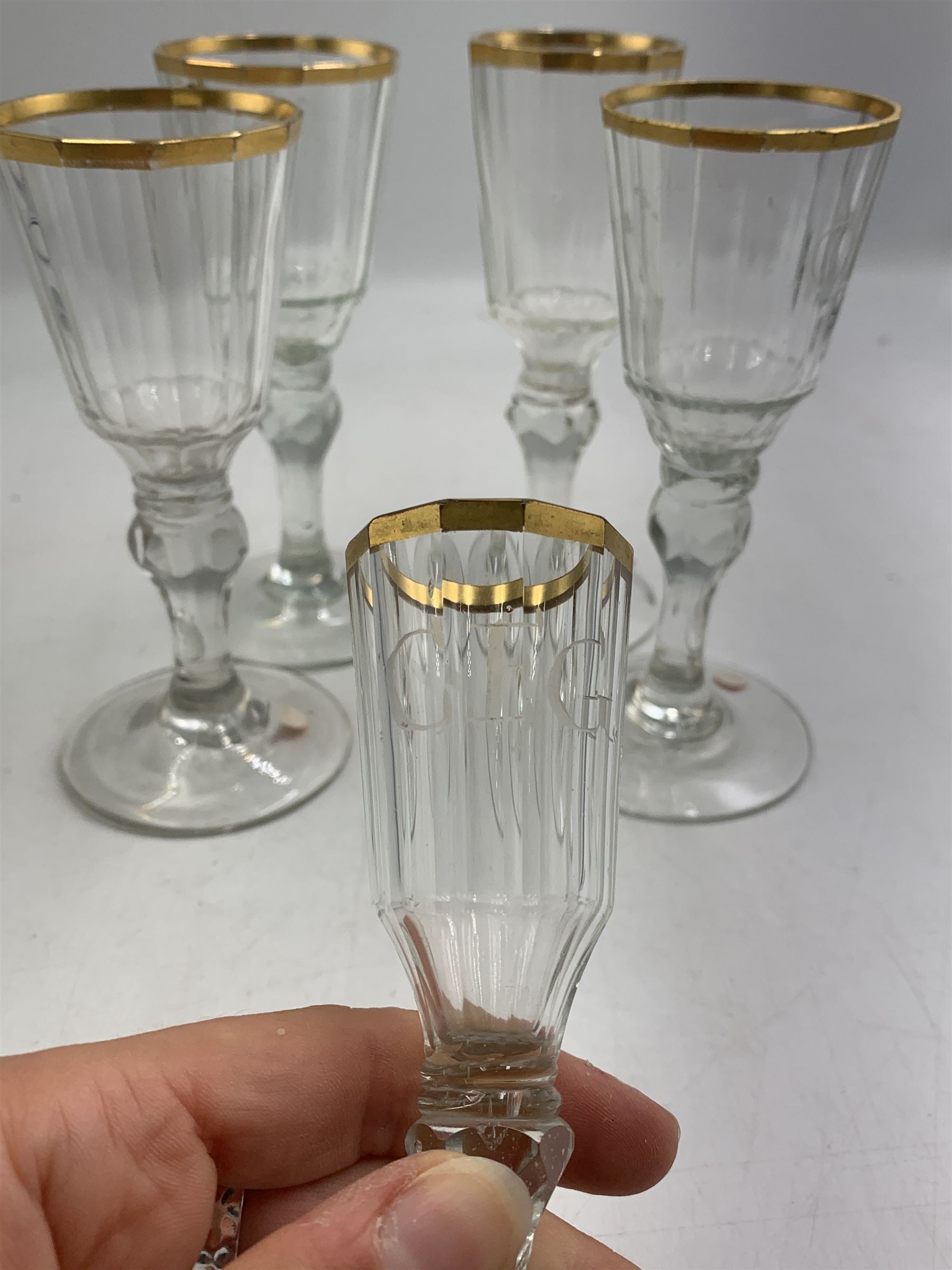 Set of four 19th century Baccarat liqueur/sherry glasses, circa 1820, with panelled bucket bowls and gilt rims, engraved CEG, to faceted knopped stems, together with another smaller example, H14cm and H12cm (5)