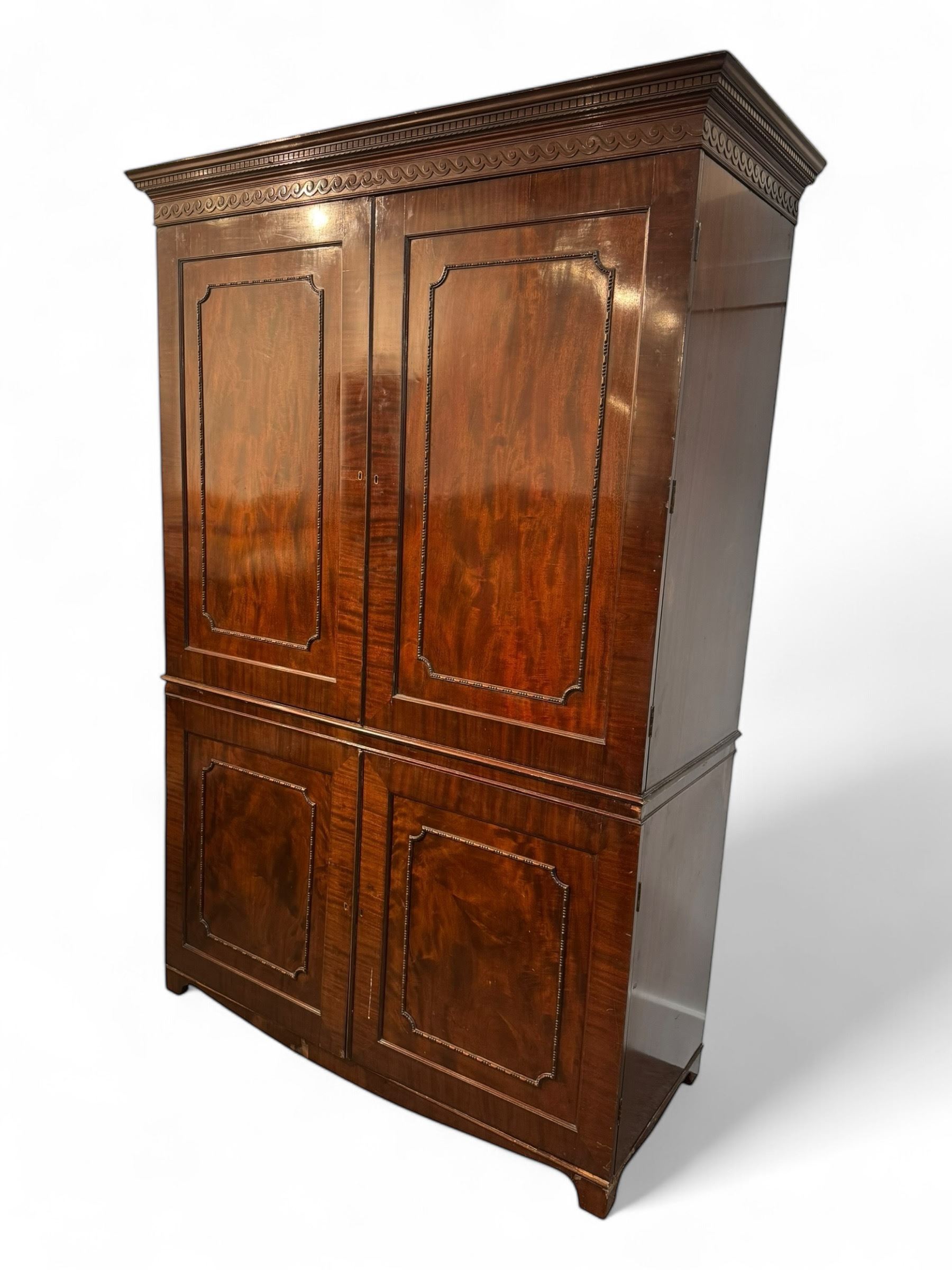 Victorian mahogany linen press, projecting cornice with dentil and scroll detailing, double panelled doors opening to an interior fitted with a brass hanging rail and coat hooks, lower section with two drawers and fitted shelves for additional storage, raised on bracket feet