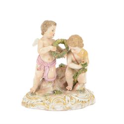 Meissen figure group modelled as two putto, one holding olive wreath and each kneeling upo...